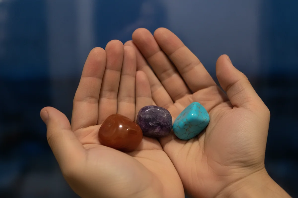 Pierre signe astrologique : un homme tient dans ses mains une cornaline, une améthyste et une turquoise, sur un fond bleu nuit
